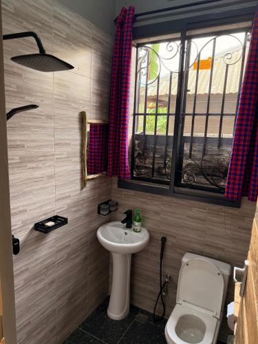 a bathroom with a sink and a toilet and a window at Baraka Home in Arusha