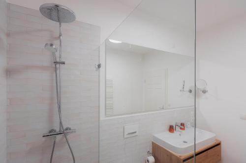 a white bathroom with a shower and a sink at Alpine Apartements Maximilian in Berchtesgaden