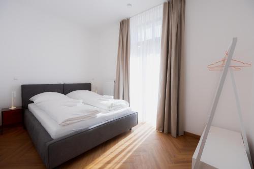 a bedroom with a bed with white sheets and a window at Alpine Apartements Maximilian in Berchtesgaden
