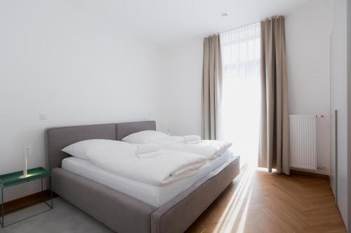 a bedroom with a bed with white sheets and a window at Alpine Apartements Maximilian in Berchtesgaden