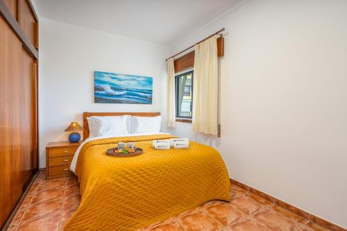 a bedroom with a bed with a yellow blanket at HostWise - Sunny Flat Near Praia da Rocha in Portimão