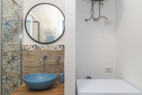 a bathroom with a blue bowl sink and a mirror at Appartamento Palau Alba in Palau
