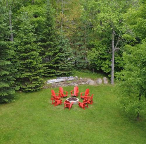 a group of red chairs and a table in the grass at Chalet La Canopée -familial par excellence MontBlanc in Mont-Blanc