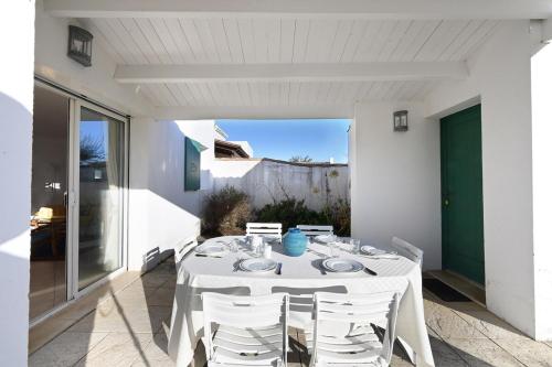 une table blanche et des chaises sur une terrasse dans l'établissement 299 Les Peupliers, à La Couarde-sur-Mer