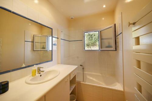 une salle de bain avec un lavabo, une baignoire et un miroir dans l'établissement 299 Les Peupliers, à La Couarde-sur-Mer