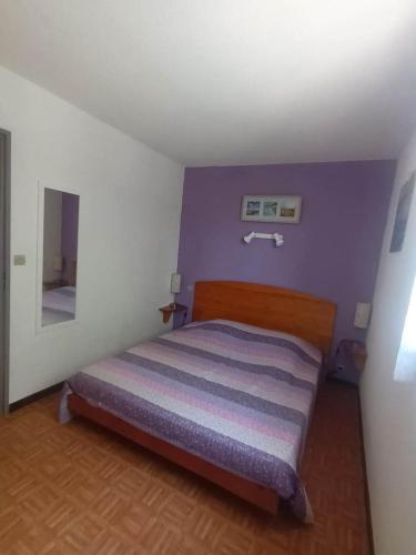 une chambre avec un lit avec un mur violet dans l'établissement Maisonnette 4places à marseillan plage., à Marseillan