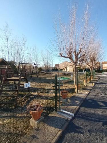 une clôture avec des plantes en pot et un arbre dans un champ dans l'établissement Maisonnette 4places à marseillan plage., à Marseillan