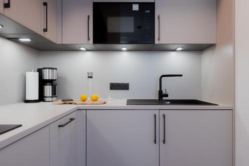 a kitchen with white cabinets and a sink at Alpine Apartements Maximilian in Berchtesgaden