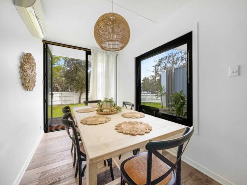 a dining room with a table and chairs and large windows at Funky Beachfront House Opposite Kawana Surf Club in Buddina