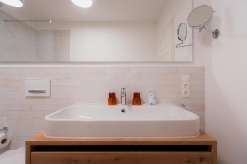 a white sink in a bathroom with a mirror at Alpine Apartements Maximilian in Berchtesgaden