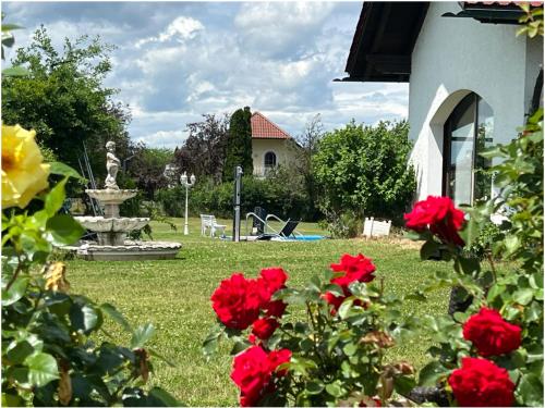 a garden with a fountain and red roses at Villa Galerie in Hohenwart