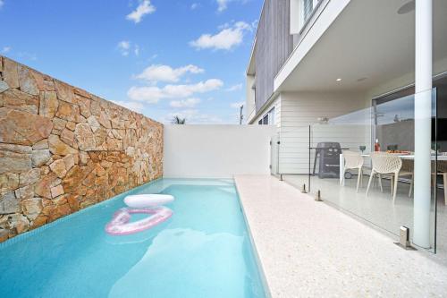 a swimming pool with a pink float in a house at Bluebird Villa - 3min Stroll to Bokarina Beach in Bokarina