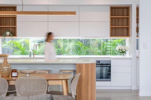a kitchen with white cabinets and a table and chairs at Bluebird Villa - 3min Stroll to Bokarina Beach in Bokarina