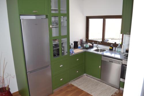 a kitchen with green cabinets and a white refrigerator at Quinta do Santo no Douro - Casa T2 in Alcarias