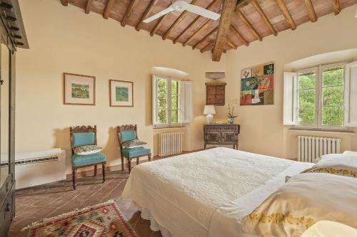 a bedroom with a large bed and two chairs at Centolivi 12 by Salogi Villas in Montecastello