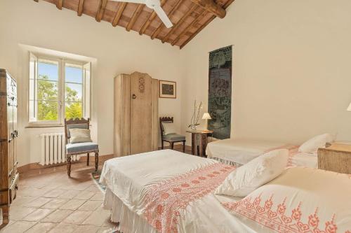 a bedroom with two beds and a chair and a window at Centolivi 12 by Salogi Villas in Montecastello