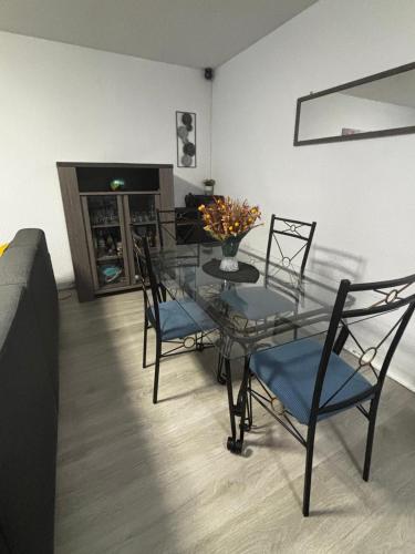 - une table et des chaises en verre dans le salon dans l'établissement Appartement T2 Le galant vert, à Aucamville