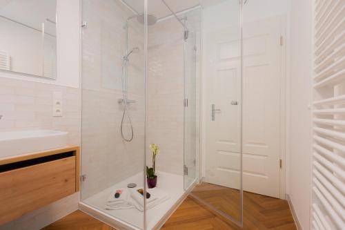 a white bathroom with a shower and a sink at Alpine Apartements Maximilian in Berchtesgaden