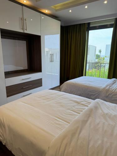 two beds in a bedroom with a tv and a window at villa c182 in Sheikh Zayed