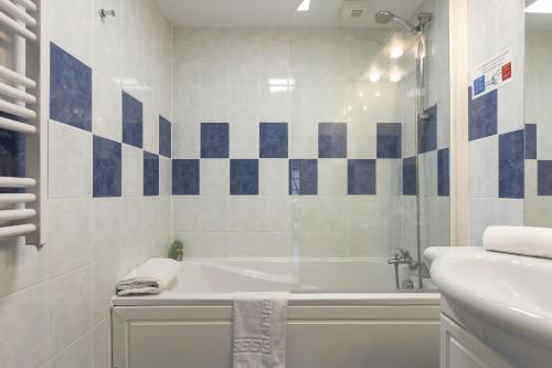 a white bathroom with a tub and a sink at Résidence Odalys Le Domaine des Rois in Bergheim
