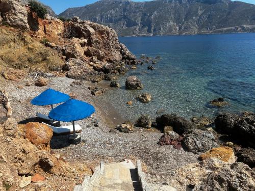 a blue umbrella and chairs on a rocky beach at Sunset Dreams Vaggelis in Skaliá