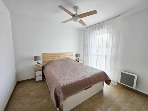 une chambre avec un lit et un ventilateur de plafond dans l'établissement Appartement neuf, 200m de la plage de Fréjus, à Fréjus