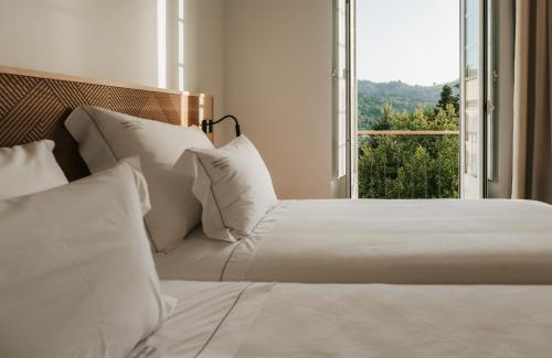 a bedroom with two beds and a large window at Casa do Parque Nature & Heritage Hotel in Castelo de Vide