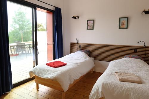 ein Schlafzimmer mit zwei Betten und einem großen Fenster in der Unterkunft La terrasse du Colombier in Lantenay