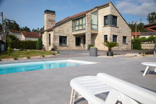 a house with a swimming pool in front of a building at GALIHOST - Villa Gandara in Ribadumia