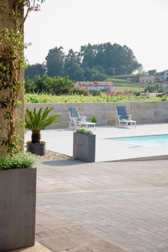 a patio with two chairs and a swimming pool at GALIHOST - Villa Gandara in Ribadumia