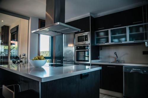 a kitchen with black cabinets and a bowl of fruit on a counter at GALIHOST - Villa Gandara in Ribadumia