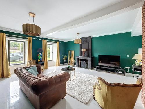 un salon avec des murs verts et un canapé et une cheminée dans l'établissement Maison en pierre proche Blayais, à Saint-Girons-dʼAiguevives