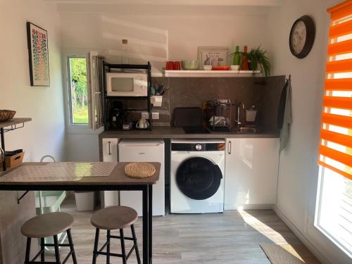 une cuisine avec un lave-linge et une table avec des tabourets dans l'établissement Appartement T1 Bis, à Gragnague
