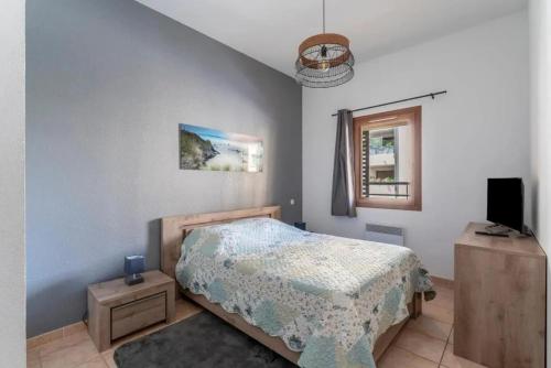 ein Schlafzimmer mit einem Bett, einem Fernseher und einem Fenster in der Unterkunft Maison charmante à Uzès avec accès à piscine partagée in Uzès