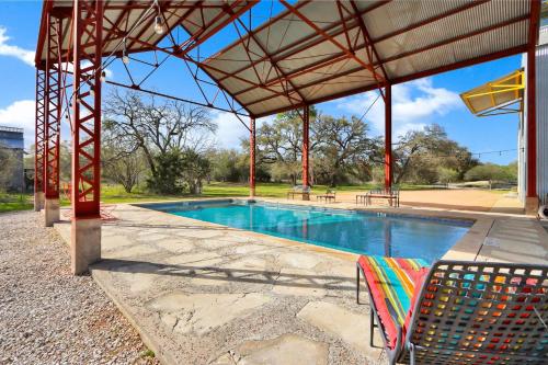 a swimming pool with a pavilion and two chairs at The Plant at Kyle in Driftwood