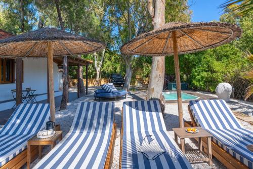 two blue and white chairs and umbrellas next to a pool at Amouage Boutique Home in Skiathos Town