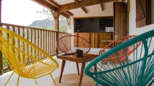 three chairs and a table on a balcony at Haut de villa, vue imprenable in Baillif