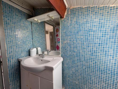 La salle de bains est pourvue d'un lavabo et d'un mur carrelé bleu. dans l'établissement Maison Montpellier Nord 10 personnes, à Montpellier