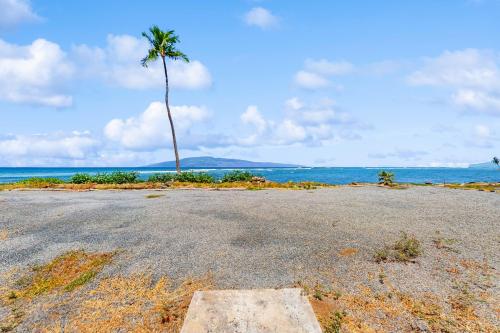 an empty parking lot with a palm tree and the ocean at Puamana 30-2 in Lahaina