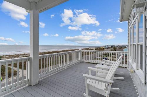 een veranda met twee witte stoelen en het strand bij Ocean View Pool Waterslide Elevator & Firepit in Oak Island