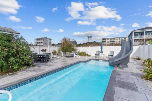 een zwembad met een glijbaan midden in een tuin bij Ocean View Pool Waterslide Elevator & Firepit in Oak Island