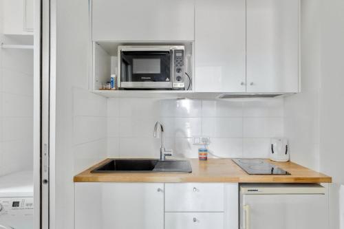une cuisine avec un évier et un micro-ondes dans l'établissement Élégant studio près de la Place de la Bastille, à Paris