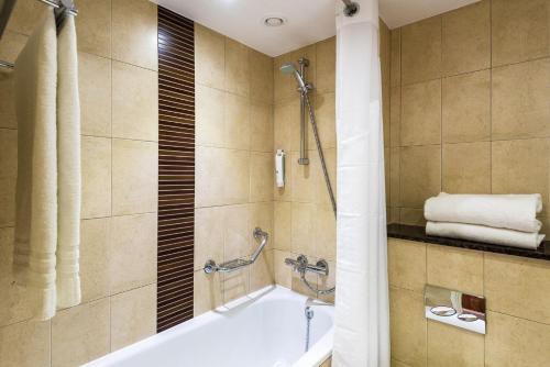 a bathroom with a tub and a shower at Holiday Inn Brighton Seafront by IHG in Brighton & Hove
