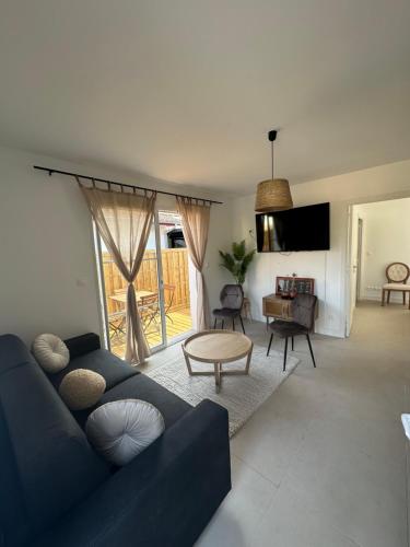 un salon avec un canapé bleu et une table dans l'établissement Maison cosy à 10 minutes de la plage, à Gujan-Mestras