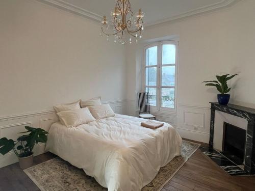 - une chambre blanche avec un lit et un lustre dans l'établissement Domaine des Étoiles du Gâtinais, 
