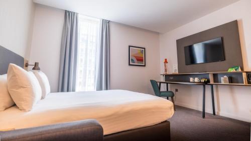 a hotel room with a bed and a desk and a tv at Holiday Inn Sunderland - City Centre by IHG in Sunderland