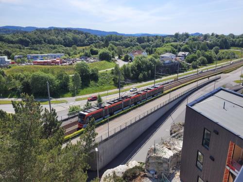 a train is on the tracks near a road at New apartment 5min to airport at Kokstad train station in Bergen
