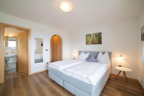 a bedroom with a large white bed and a bathroom at Pension Klausthaler in Meltina