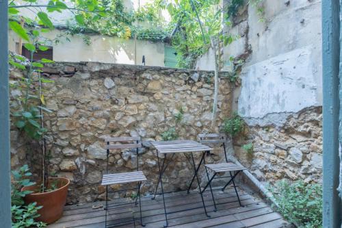 une table et deux chaises à côté d'un mur en pierre dans l'établissement Le Petit Paradis, à Marseille