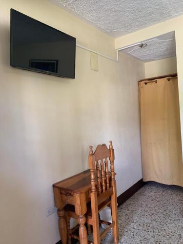 a room with a wooden chair and a television on a wall at Hotel Posada Kamol Bey in Panajachel